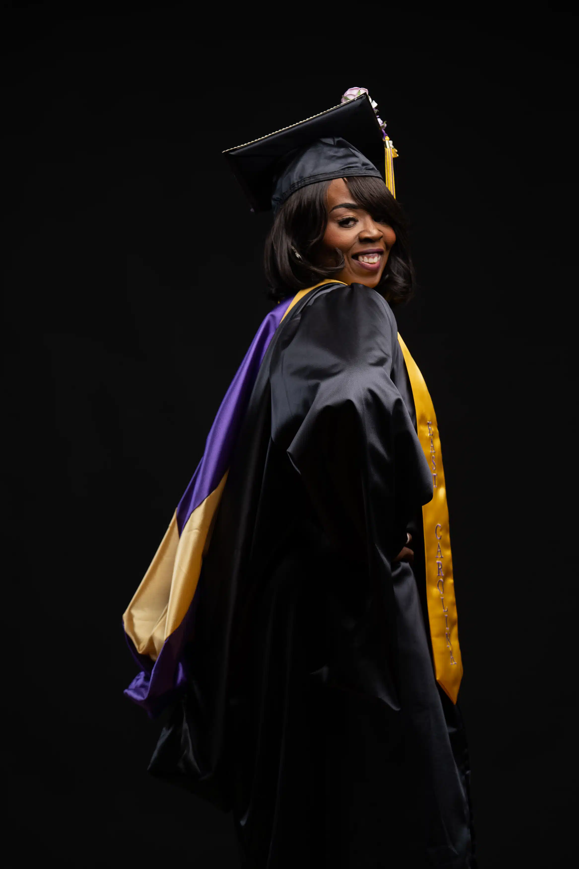 Woman wearing her cap and gown for East Carolina University (ECU) and posing for her graduation photos.
