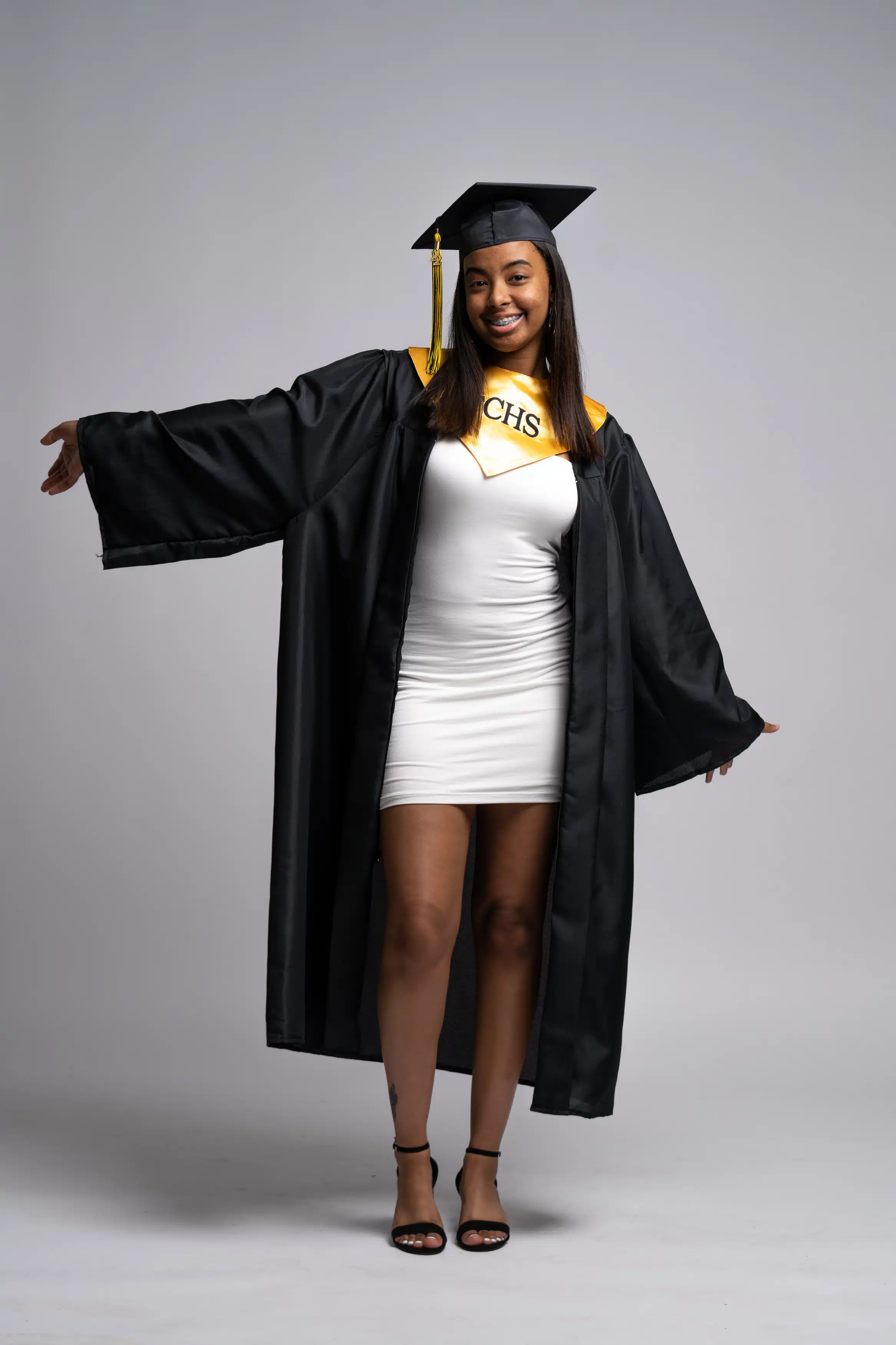 Woman wearing her cap and gown for East Carolina University (ECU) and posing for her graduation photos. While being in a photography studio located in greenville, nc