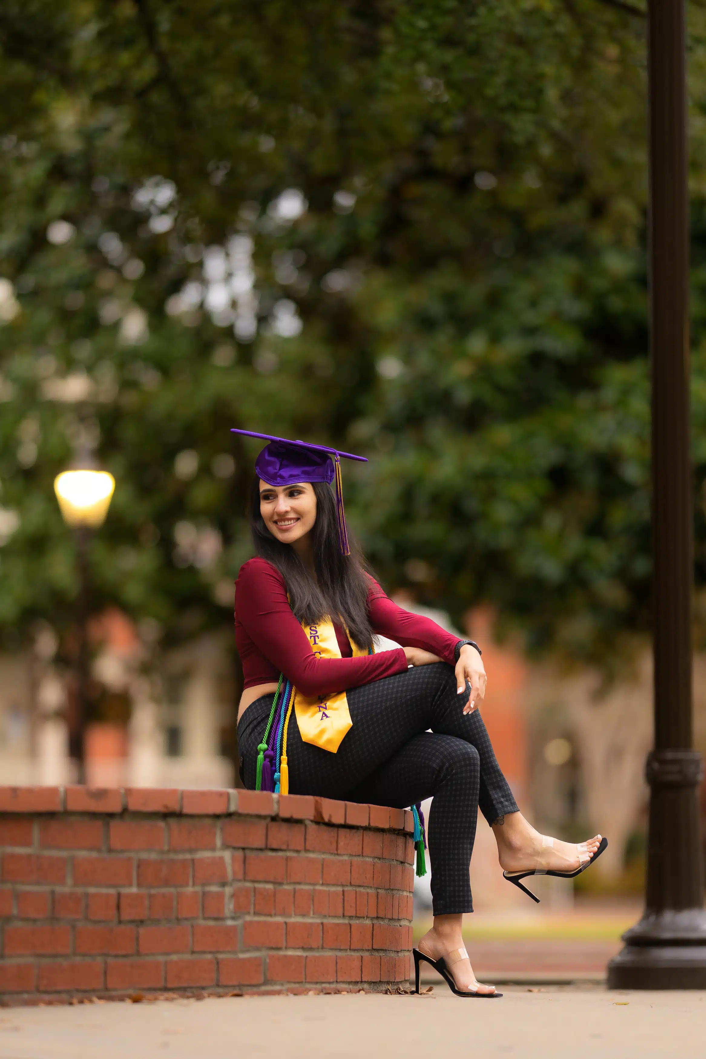 Woman wearing her cap and gown for East Carolina University (ECU) and posing for her graduation photos.