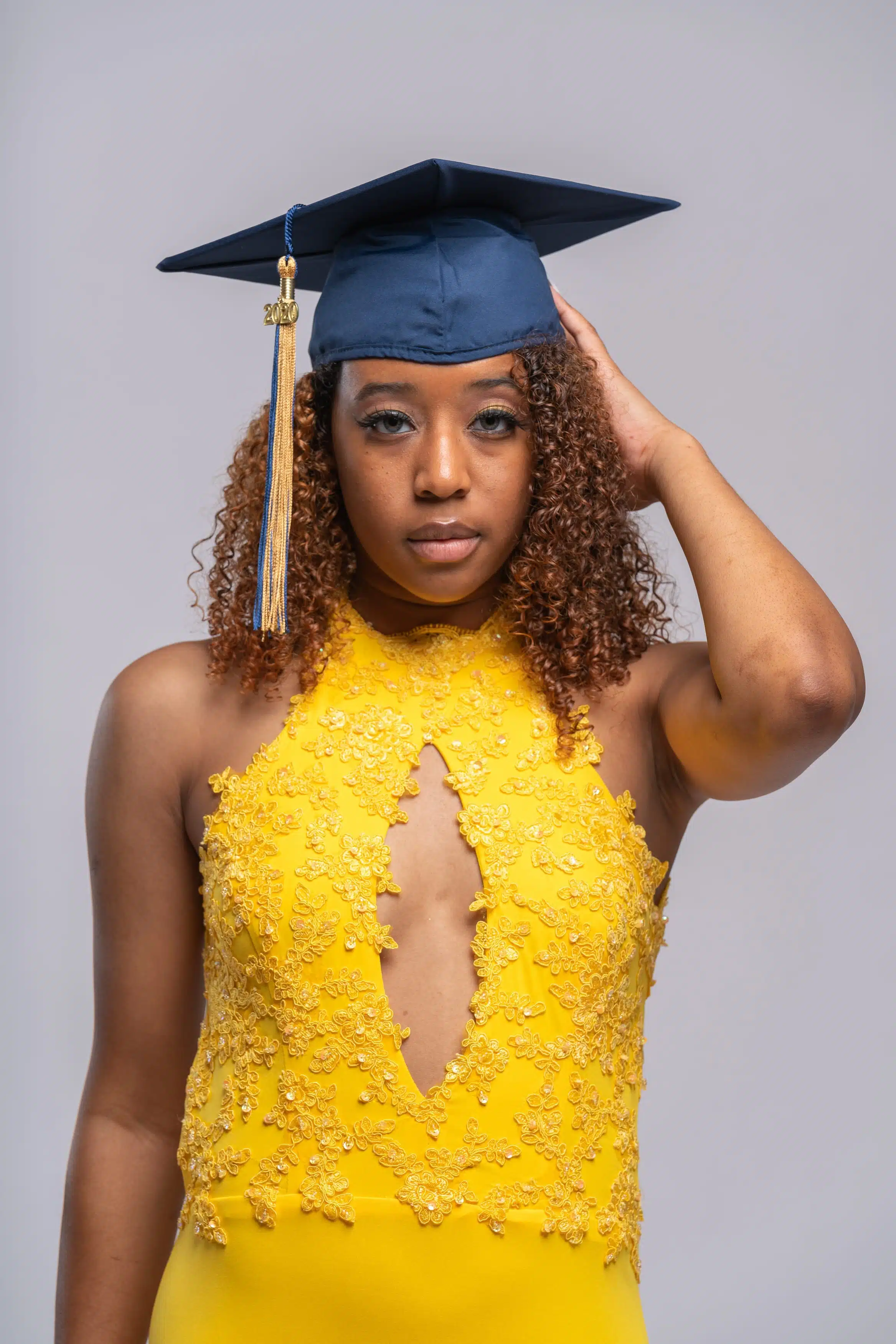 Girl with her graduation cap on and in her graduation outfit for the studio graduation photography session in studio of True Essence Photography.