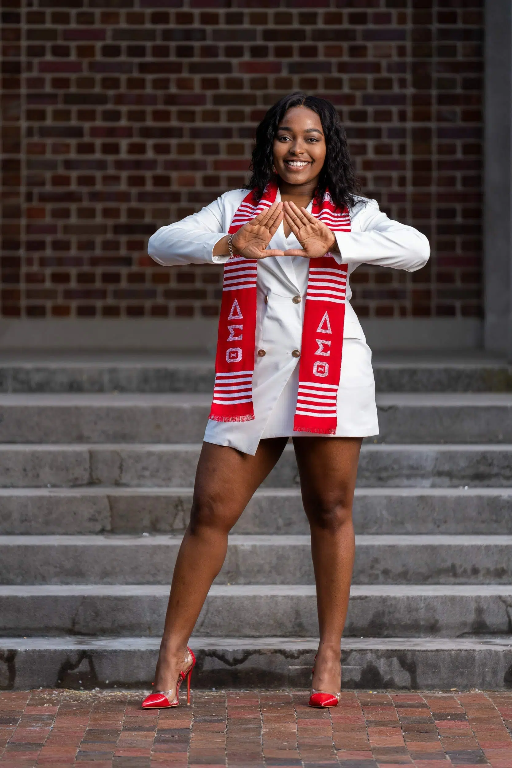 Black woman part of the delta sorority posing for her graduation photos at UNC College Campus.